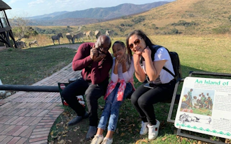 Tourists enjoying a scenic view with zebras in the background at a Durban nature reserve.