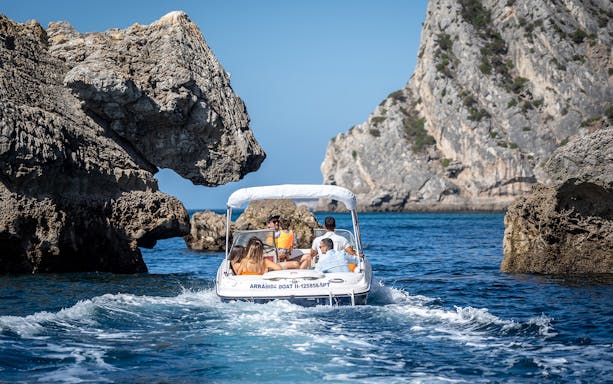 Boat navigating between rocky cliffs on a half-day rental in Arrábida, Portugal.