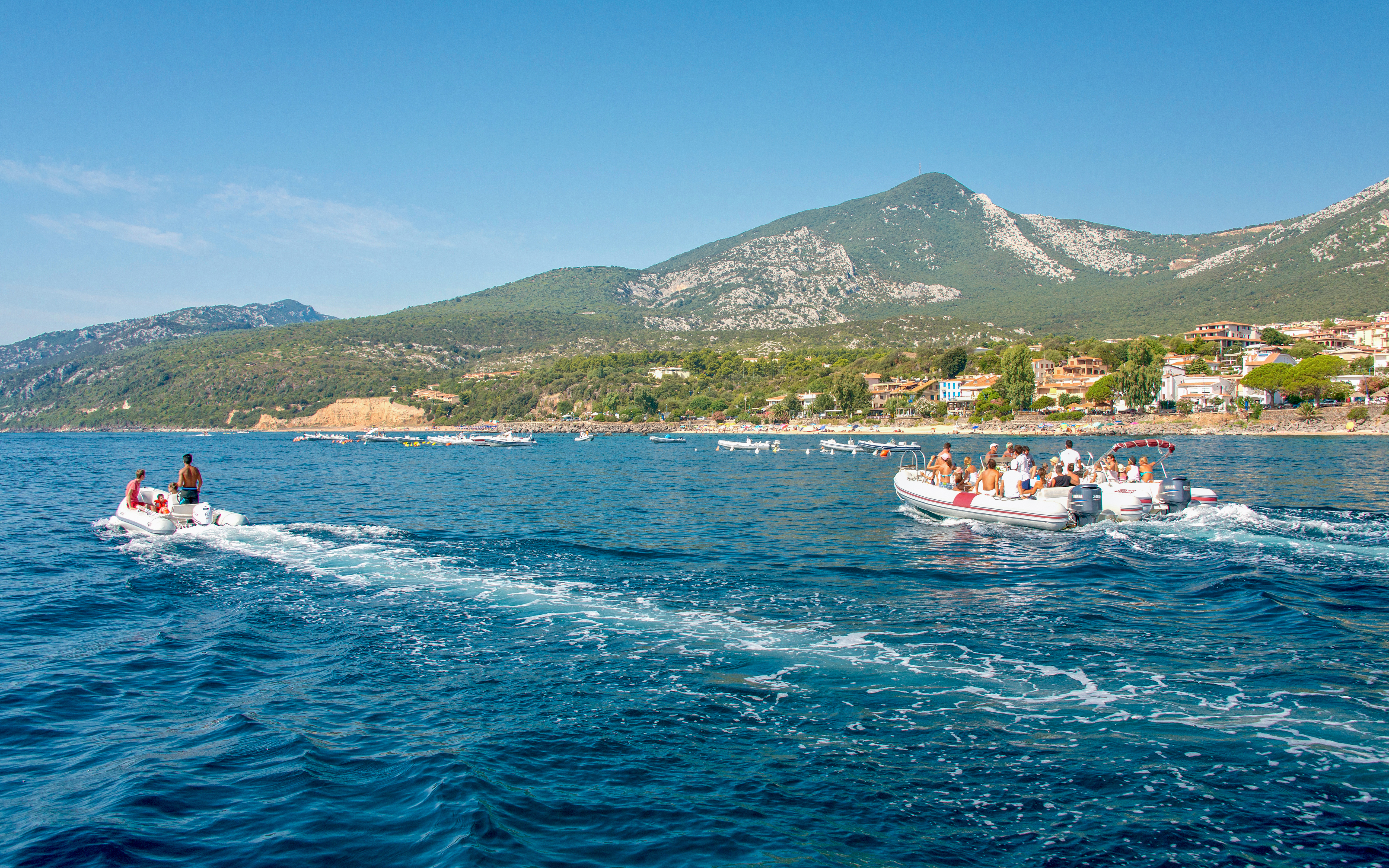 Tourist boats and dinghies departing Cala Gonone port, Gulf of Orosei, Sardinia, Italy.
