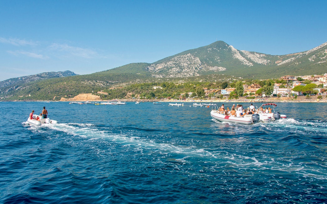 Tourist boats and dinghies departing Cala Gonone port, Gulf of Orosei, Sardinia, Italy.
