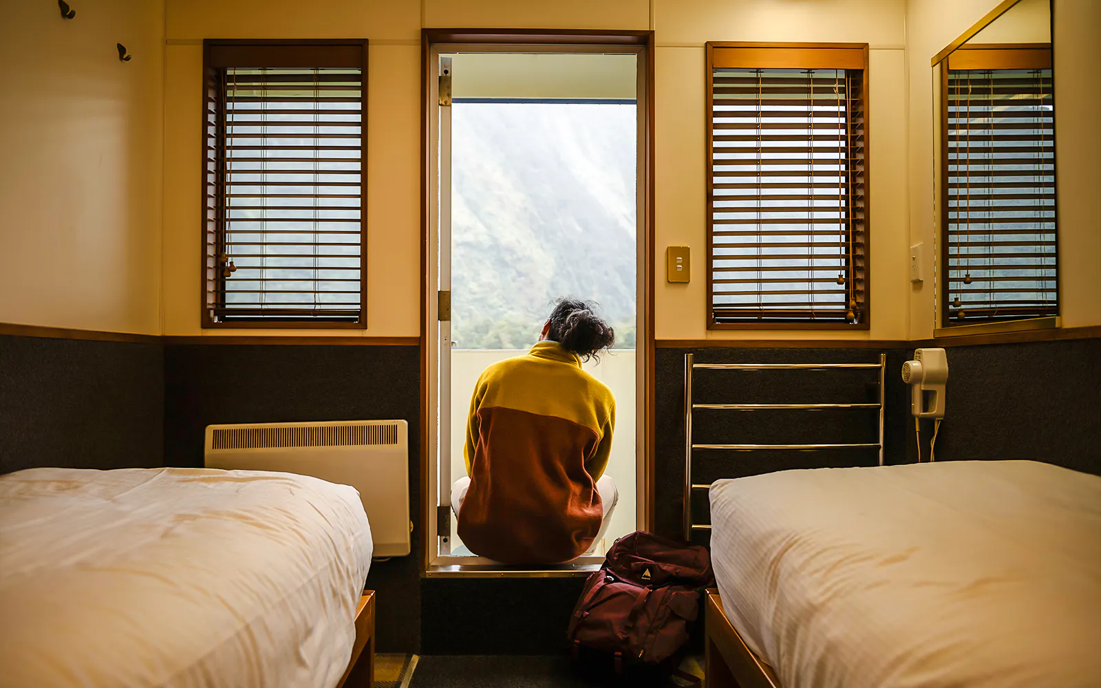 Person sitting in a cabin doorway on a ship, overlooking Milford Sound.