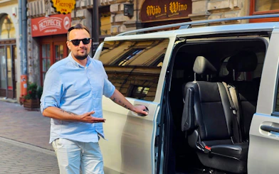 Man standing by an open van door for round-trip AC transfers in Krakow, Poland.