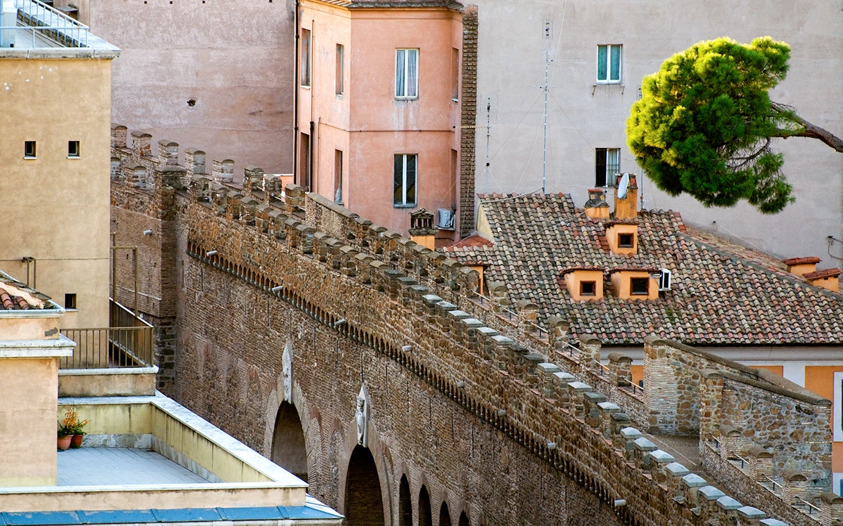 Passetto di Borgo stone wall with arches and adjacent buildings in Rome.
