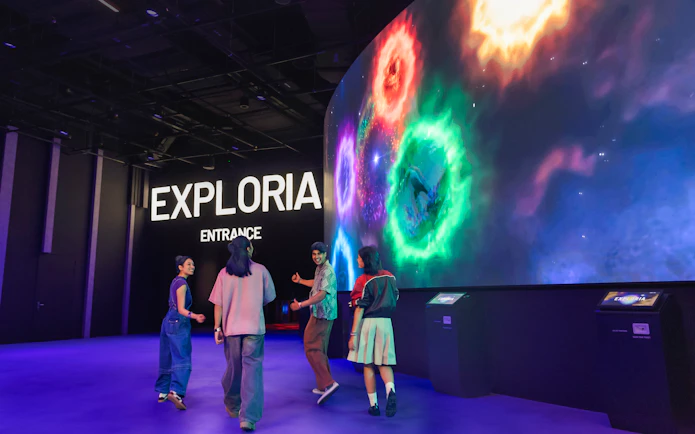 Visitors at Exploria entrance, Mandai Wildlife, viewing interactive cave spider exhibit displays.