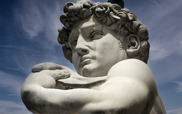 Statue of David in Florence, Italy, viewed from below against a blue sky.