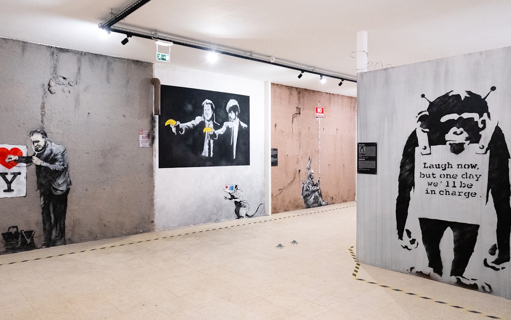 Banksy artwork in Lisbon museum featuring iconic graffiti and stencils.