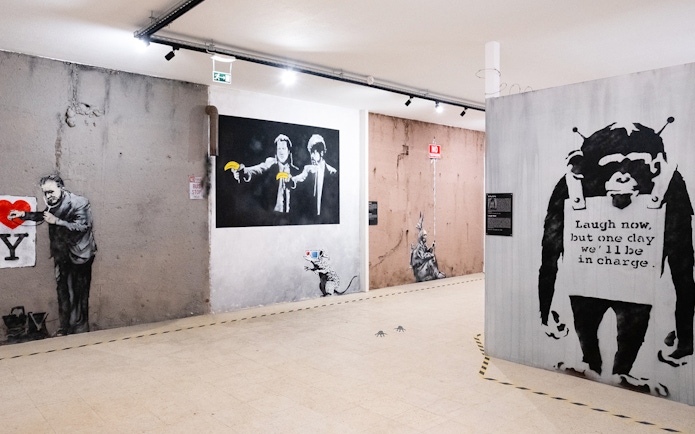 Banksy artwork in Lisbon museum featuring iconic graffiti and stencils.