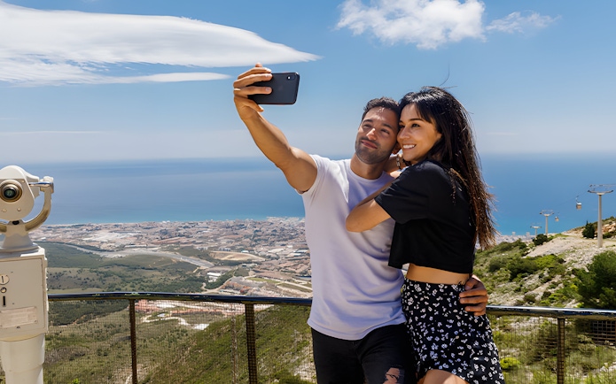 Couple taking selfie with panoramic view from Mount Calamorro, Benalmádena, Spain.