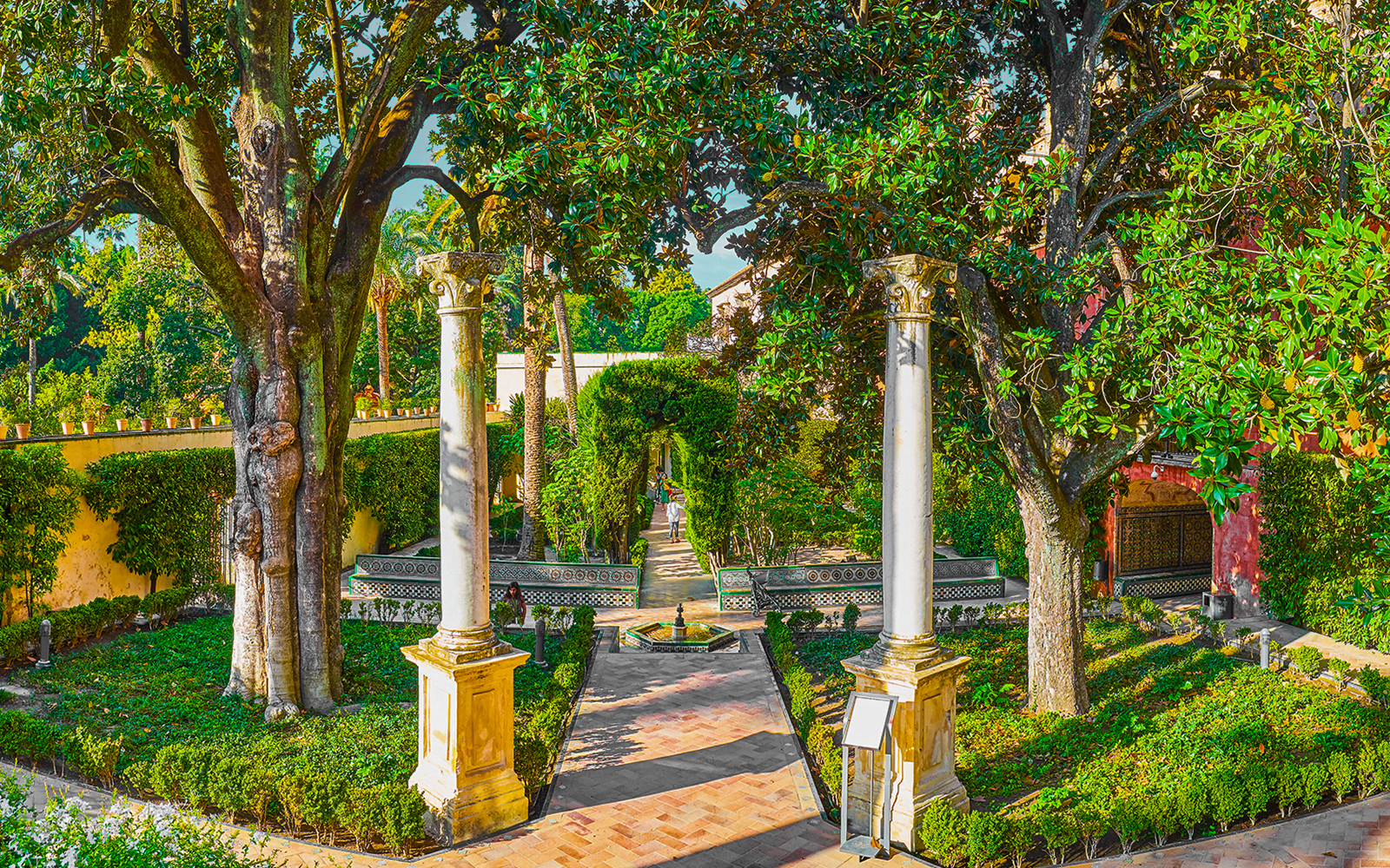The Dance's Garden fountain in Royal Alcazar Garden, Seville, Spain, surrounded by lush greenery.