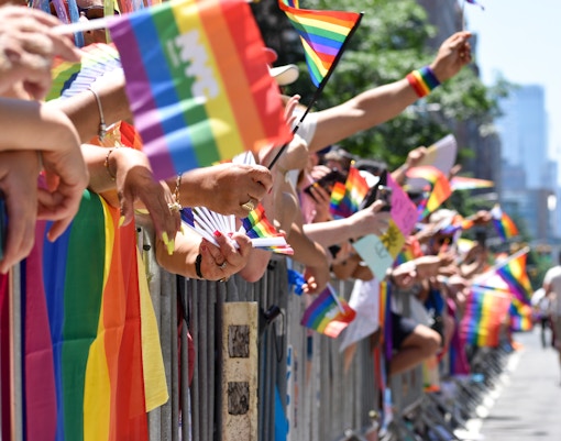 Colorful pride parade with participants holding rainbow flags in New York City.