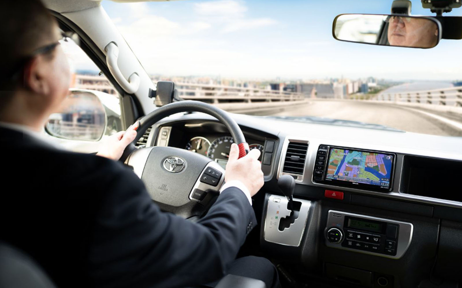 Driver navigating Kansai Airport shared shuttle van with GPS, heading towards hotel drop-off.