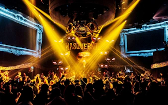 DJ performing at The Masquerade by Claptone, Ibiza nightclub with vibrant crowd and lights.