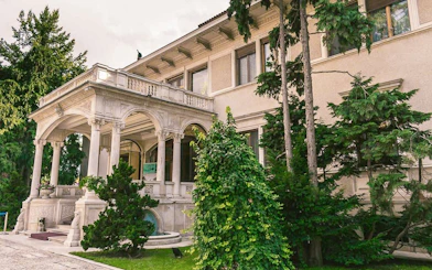 Entrance of Ceausescu Mansion surrounded by greenery in Bucharest.