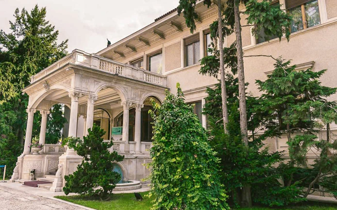 Entrance of Ceausescu Mansion surrounded by greenery in Bucharest.