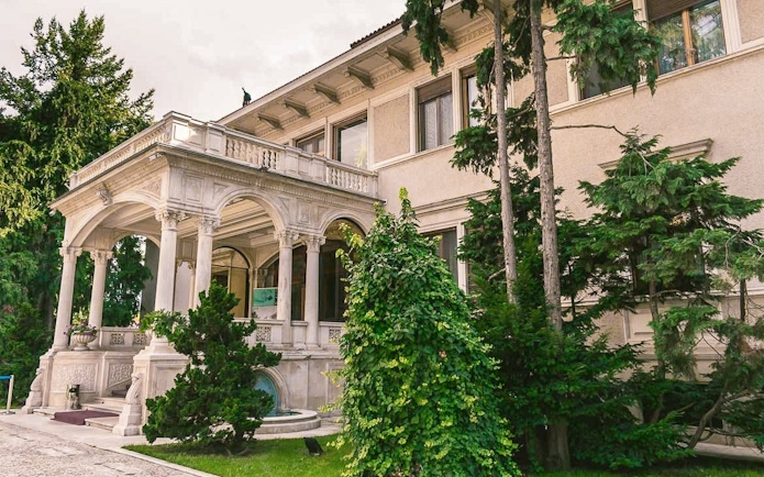 Entrance of Ceausescu Mansion surrounded by greenery in Bucharest.