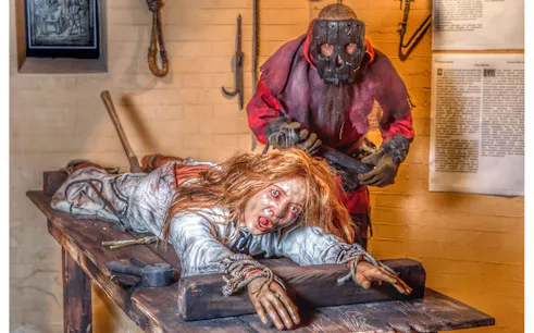 Medieval Torture Museum exhibit with a mannequin on a rack and a masked figure.