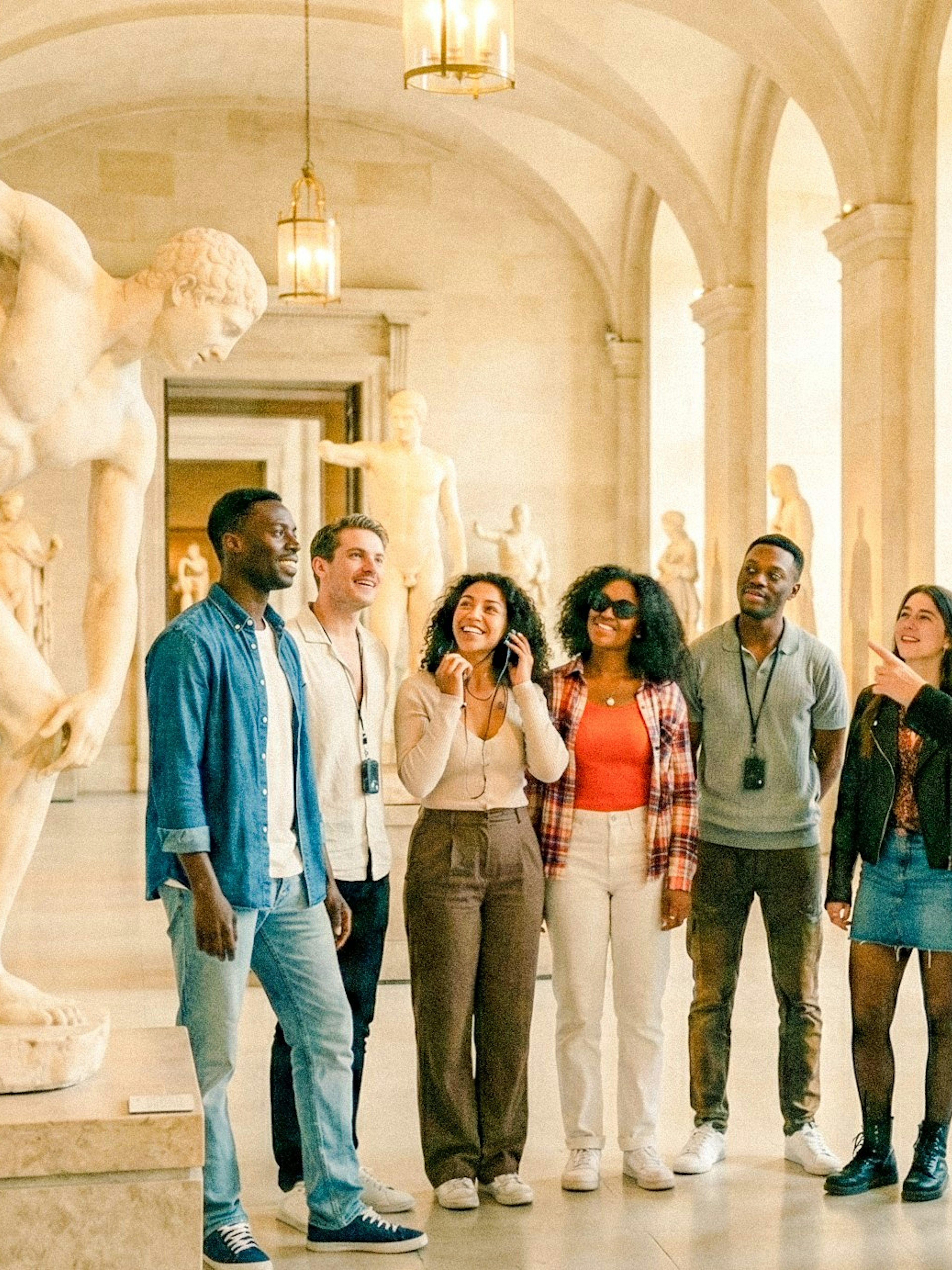 Tour group with guide in Louvre Museum, Paris, viewing classical sculptures.