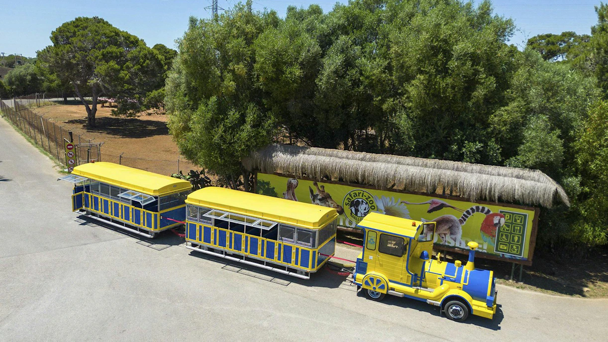 Safari zoo train at Mallorca with yellow and blue carriages near animal mural.