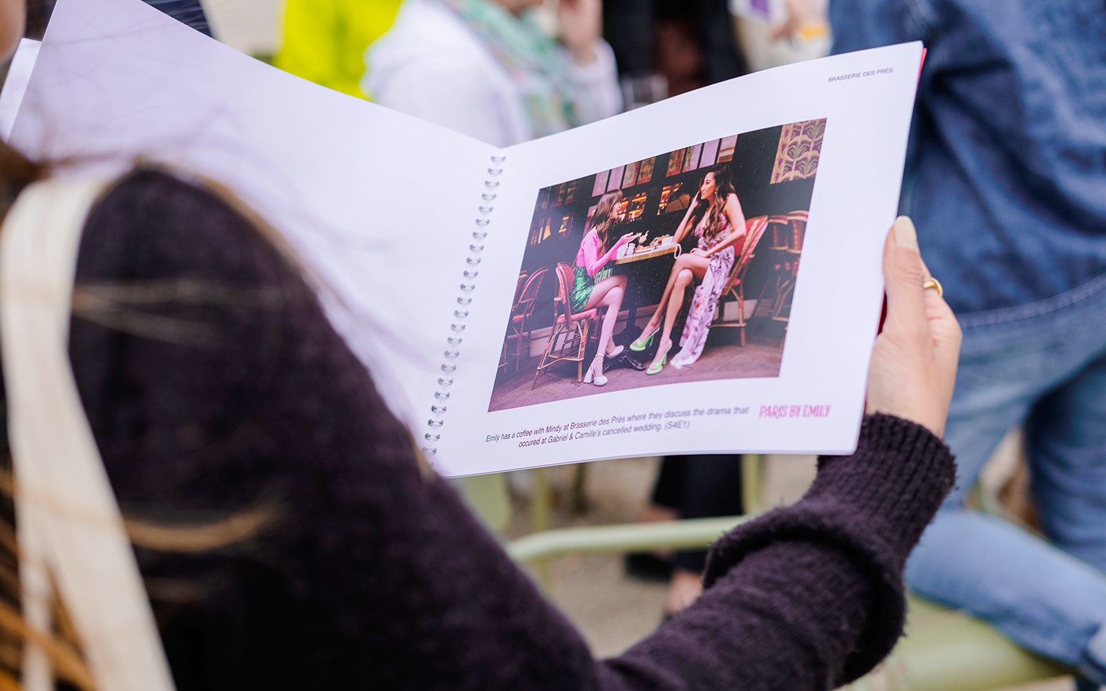 Person holding a booklet with a scene from Emily in Paris during a food tour.
