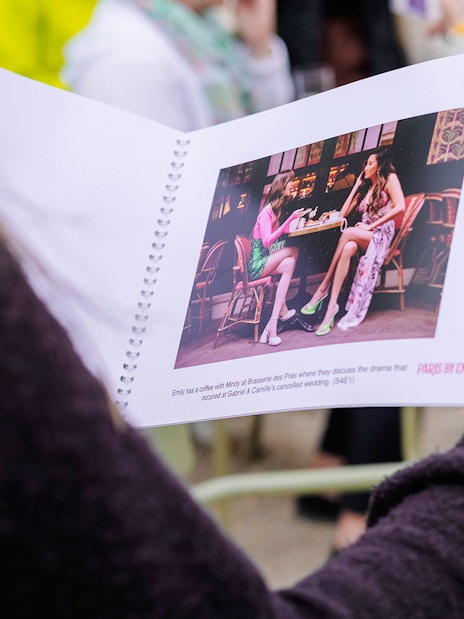 Person holding a booklet with a scene from Emily in Paris during a food tour.