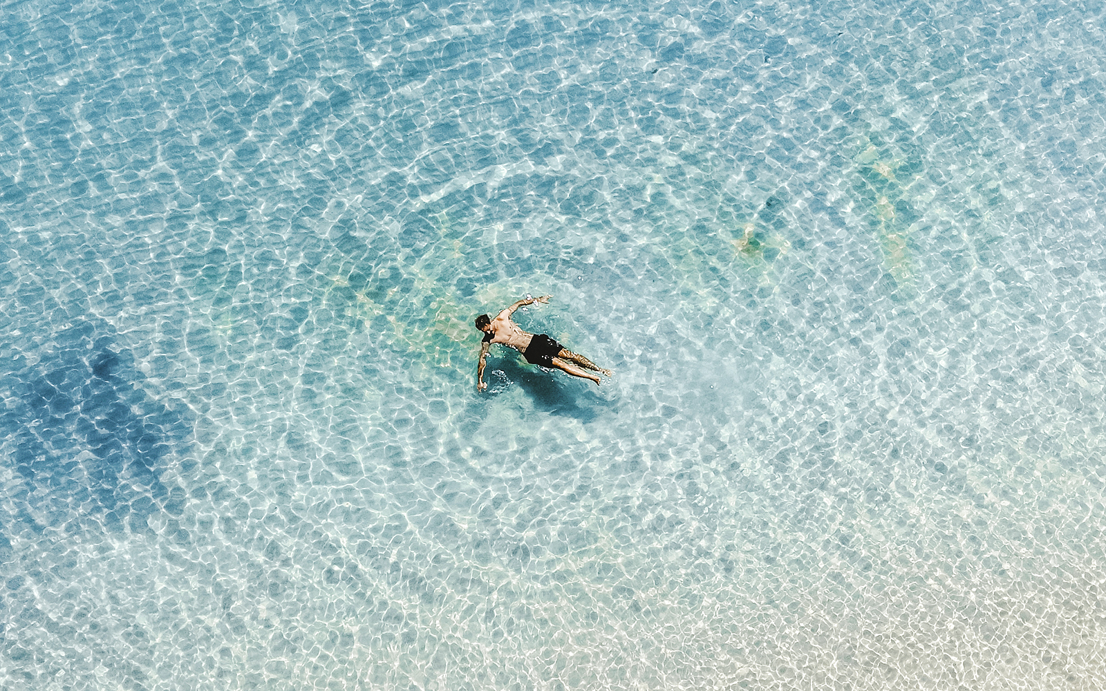 Man swimming in clear waters at Whitehaven Beach, Whitsundays, Great Barrier Reef.