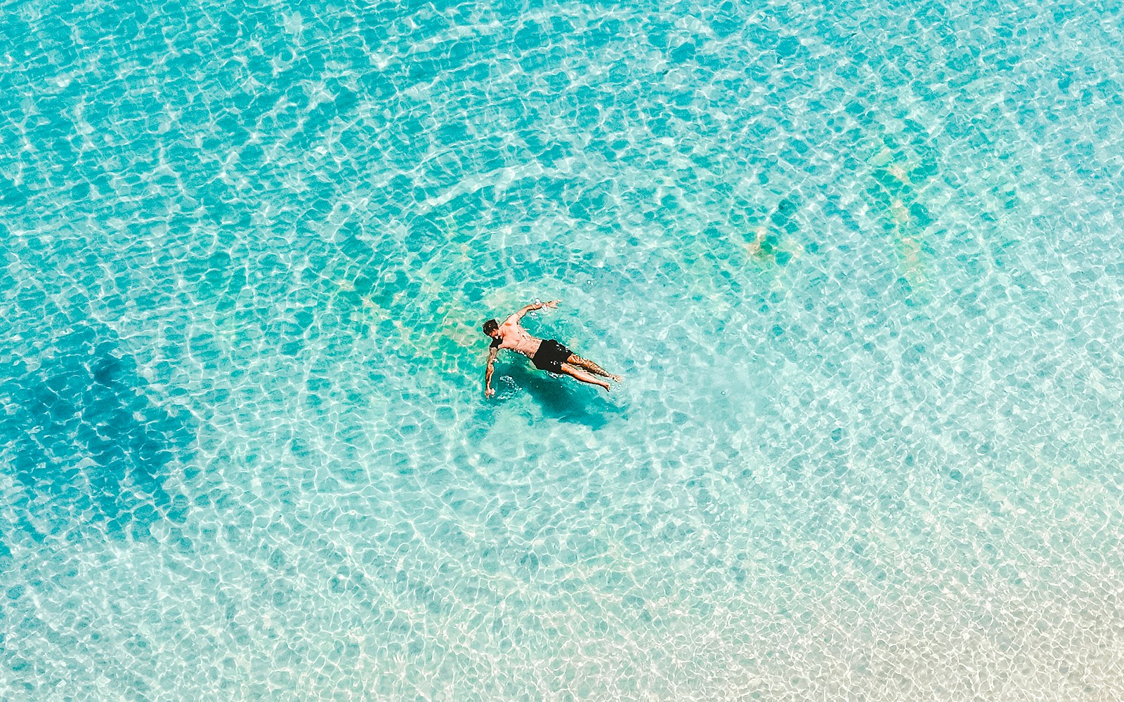 Man swimming in clear waters at Whitehaven Beach, Whitsundays, Great Barrier Reef.