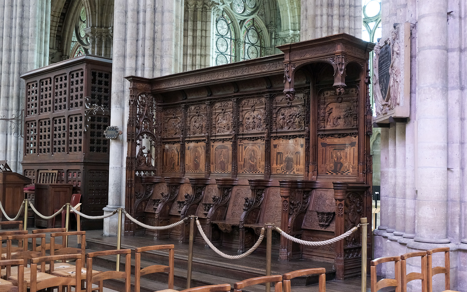 Basilica of Saint-Denis interior with detailed wooden choir stalls and stained glass windows, Paris, France.