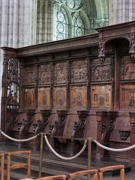 Basilica of Saint-Denis interior with detailed wooden choir stalls and stained glass windows, Paris, France.
