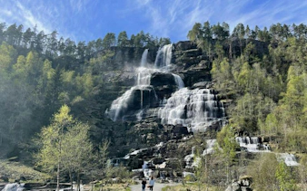 Waterfall stop on Bergen to Flåm Railway and Nærøyfjord UNESCO Cruise tour, surrounded by lush forest.