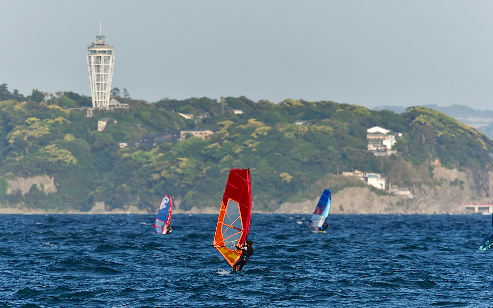 Windsurfers near Enoshima Island with Enoshima Sea Candle in the background.