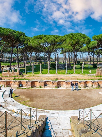 Ancient Roman theater ruins surrounded by trees in Ostia Antica, Rome.