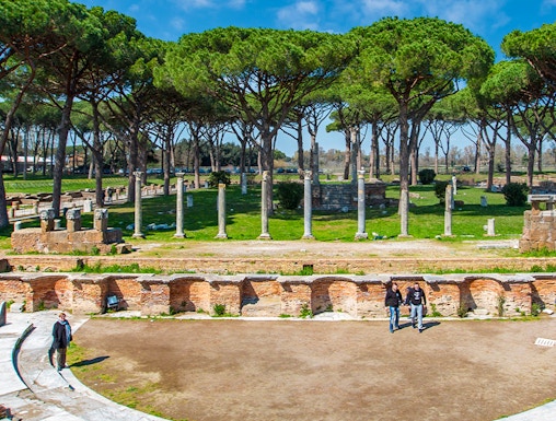 Ancient Roman theater ruins surrounded by trees in Ostia Antica, Rome.