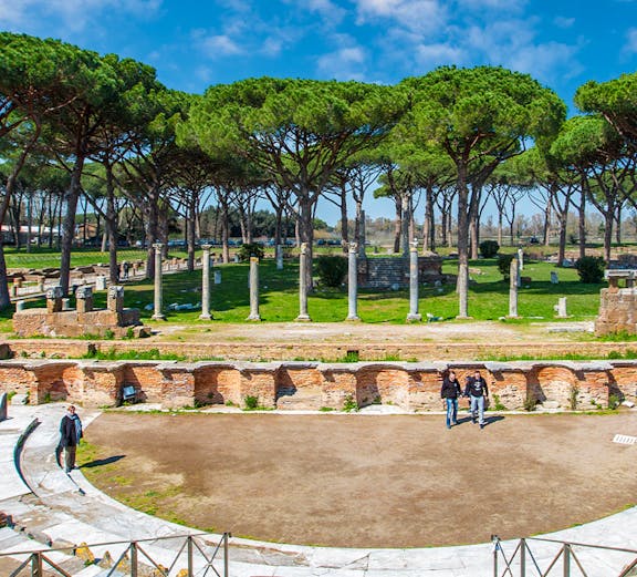 Ancient Roman theater ruins surrounded by trees in Ostia Antica, Rome.