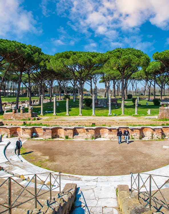 Ancient Roman theater ruins surrounded by trees in Ostia Antica, Rome.