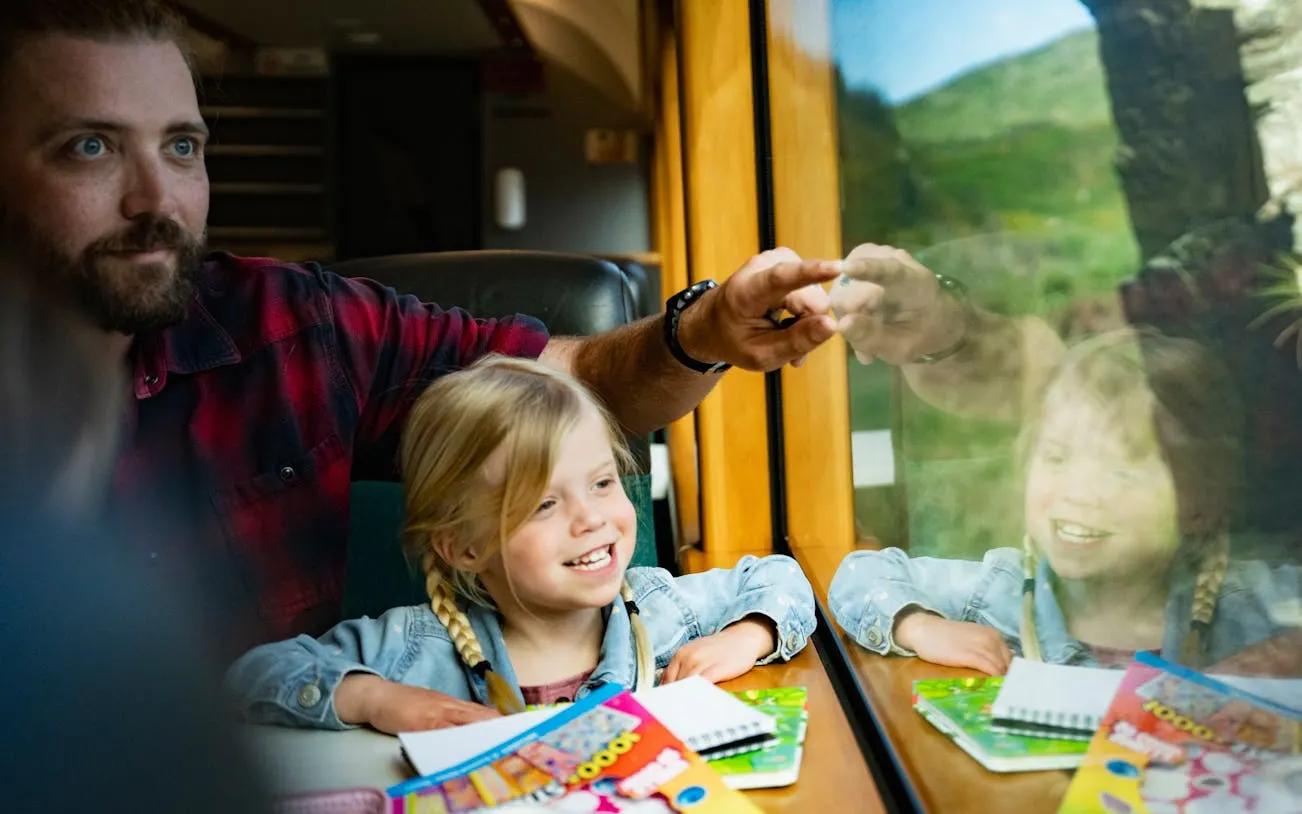 Father and daughter enjoying views on Taieri Gorge Scenic Rail Journey, New Zealand.