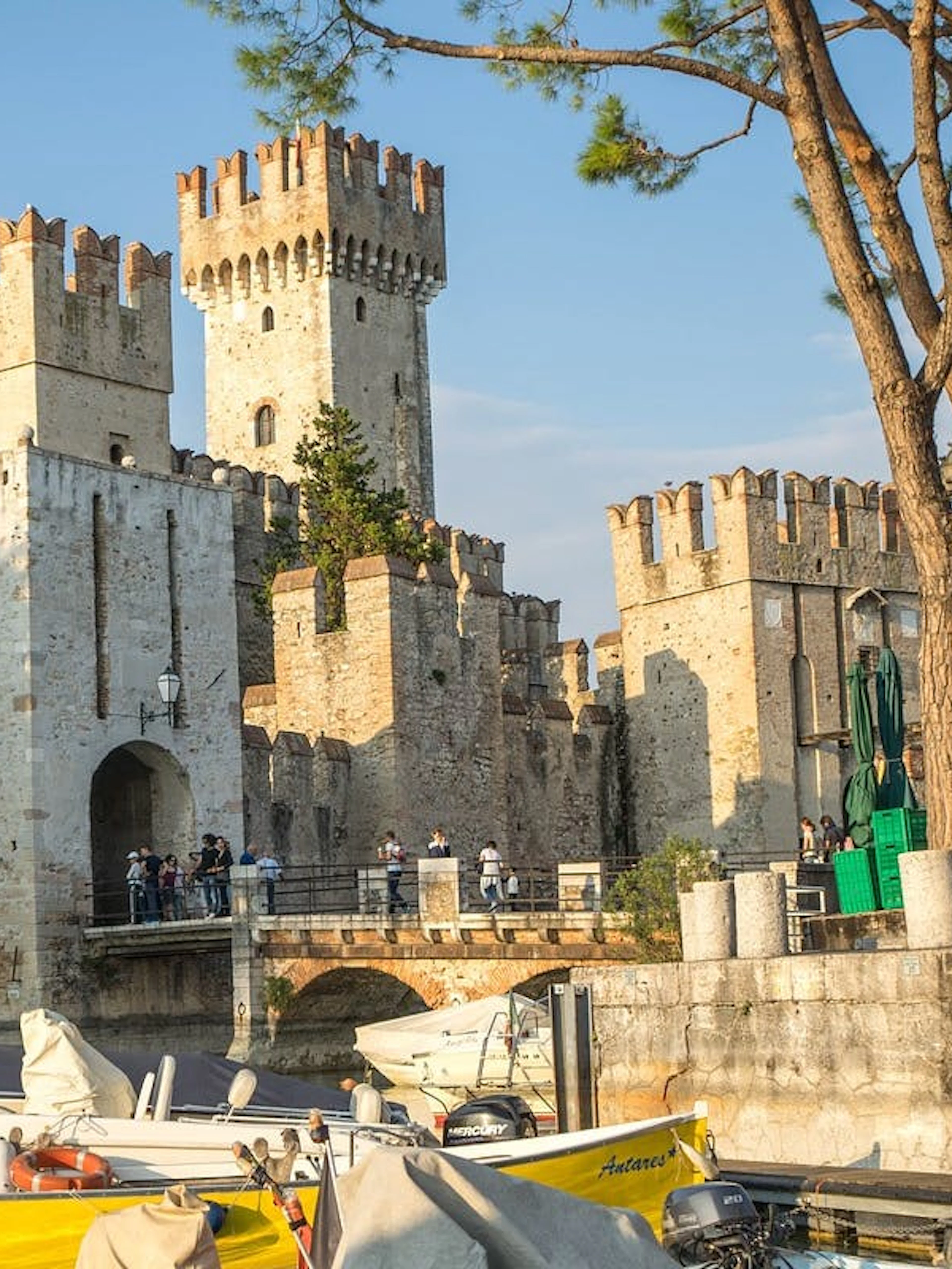 Scaliger Castle in Sirmione with boats docked nearby, part of a full-day tour from Verona.