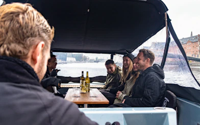 Group enjoying canal cruise on covered boat with city view.