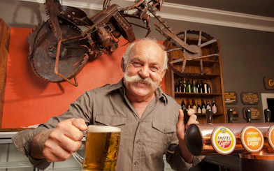 Man serving beer at Riverhead Tavern during scenic boat cruise.
