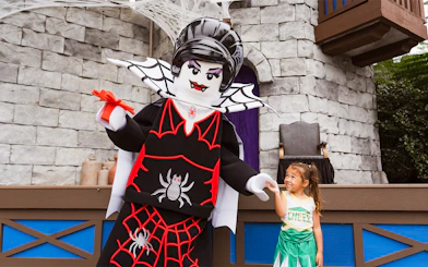 SpiderLady character at Brick or Treat event, Legoland Florida, interacting with a child.