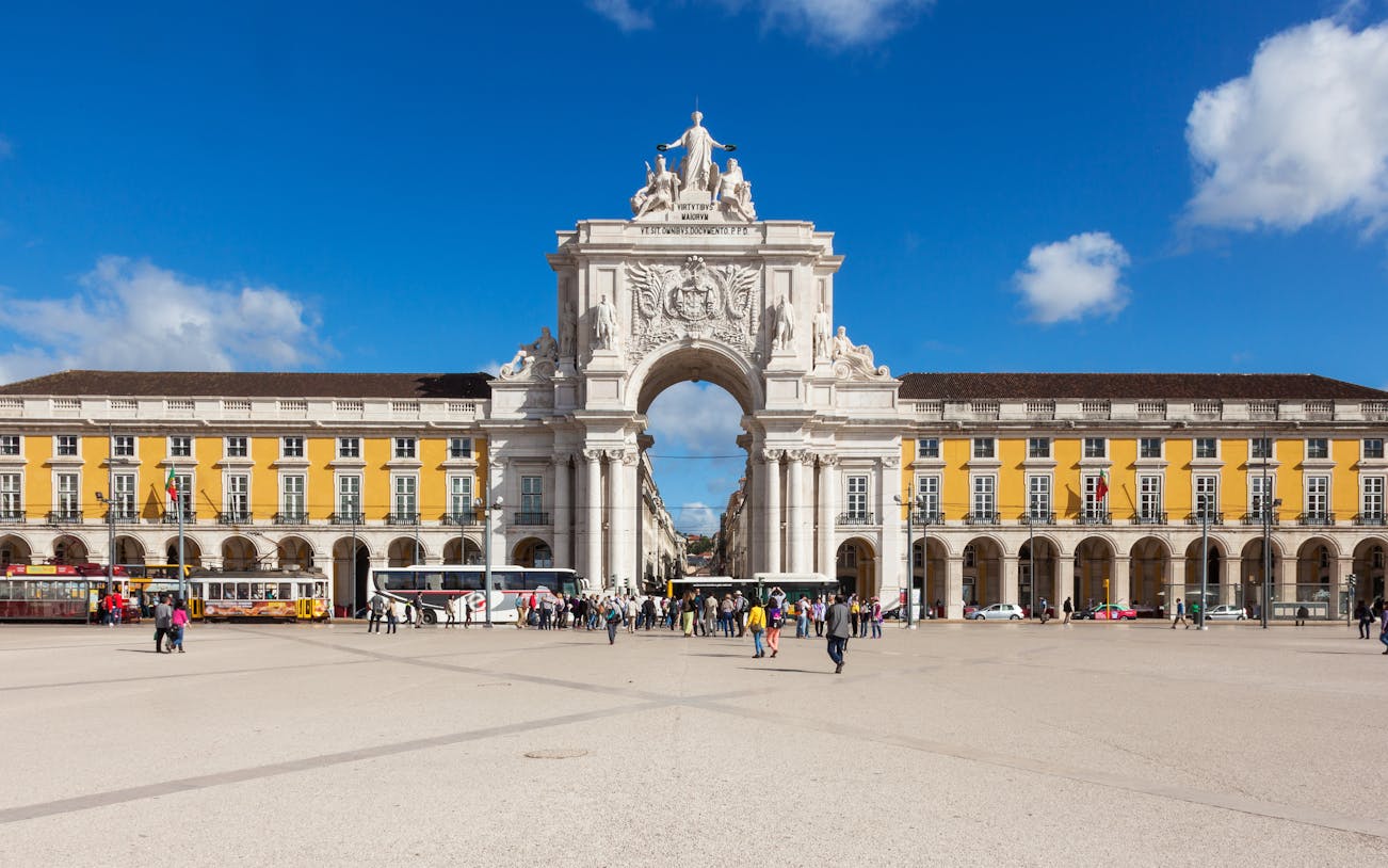 Rua Augusta Arch in Lisbon with people walking in the plaza.