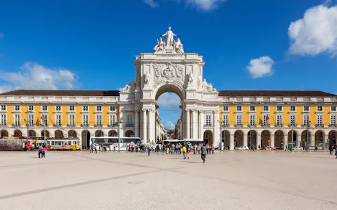 Rua Augusta Arch in Lisbon with people walking in the plaza.