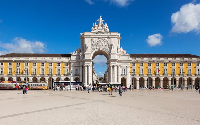 Rua Augusta Arch in Lisbon with people walking in the plaza.