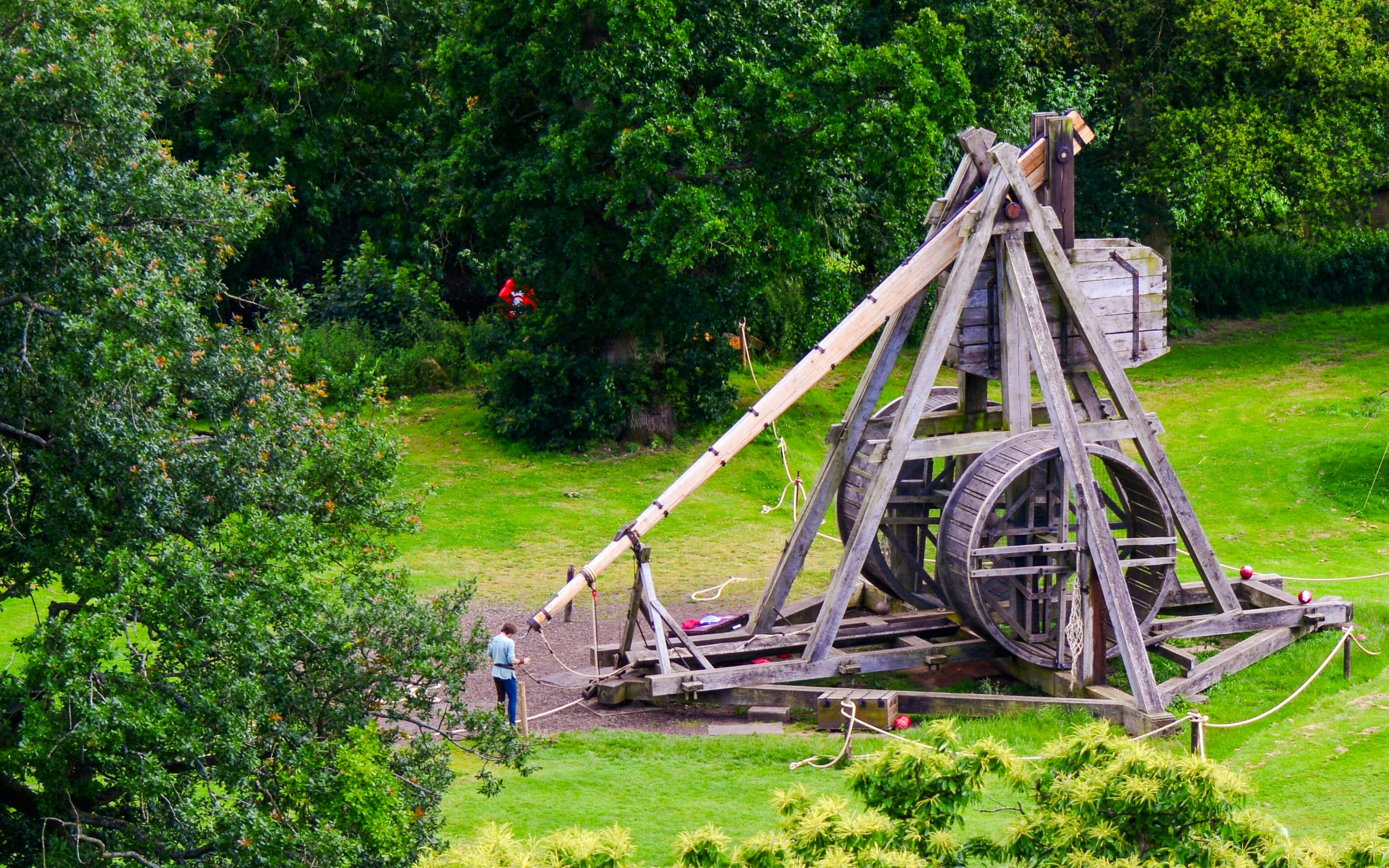 Trebuchet display in the Trebuchet Area at Warwick Castle, surrounded by greenery.