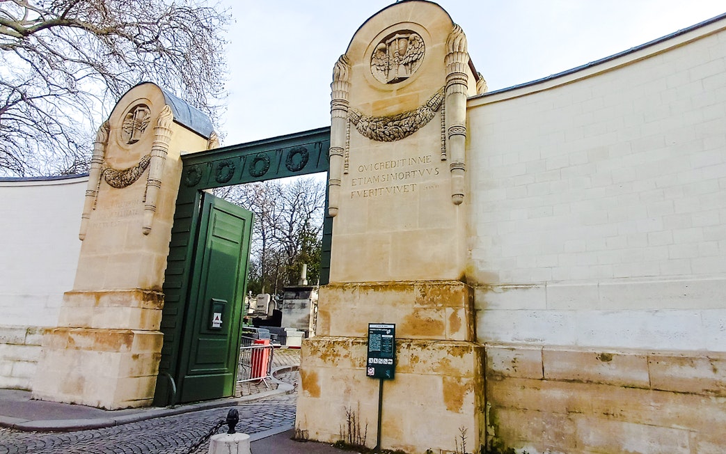 Père Lachaise Cemetery entrance with ornate stone pillars in Paris, France.