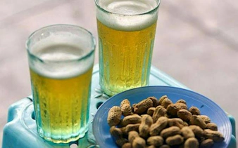 Two glasses of beer and a plate of peanuts on a table in Hanoi Old Quarter.