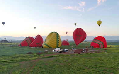 Hot air balloons preparing for sunrise flight over Marrakesh fields.