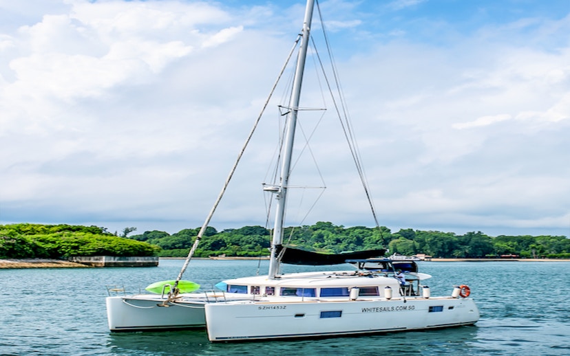 Private yacht anchored in a scenic bay with lush greenery in the background.