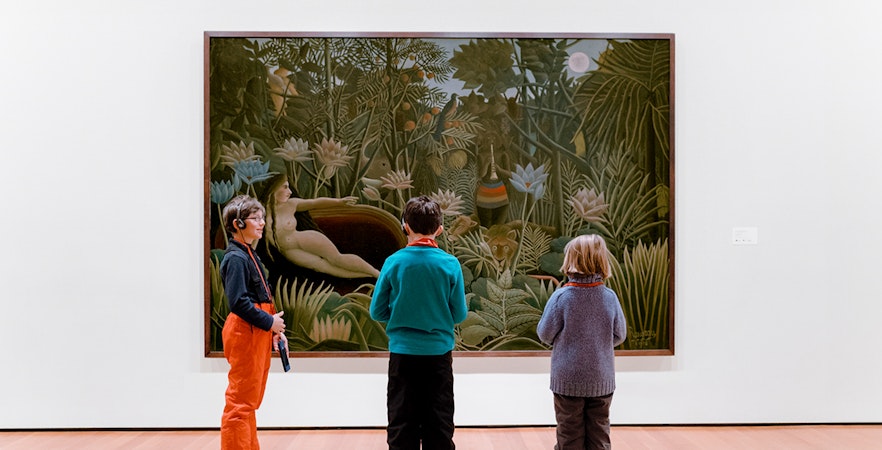 Children viewing a jungle-themed painting in an art museum.