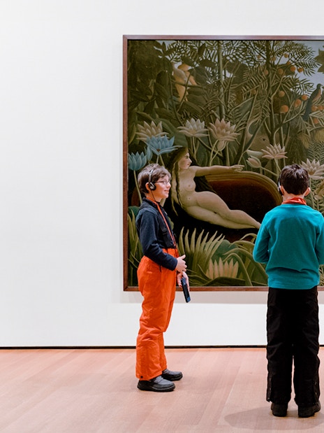 Children viewing a jungle-themed painting in an art museum.