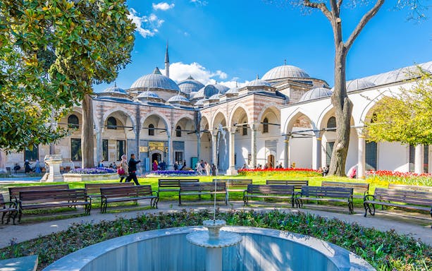 Topkapi Palace Courtyard with fountain, benches, and arched colonnade in Istanbul.